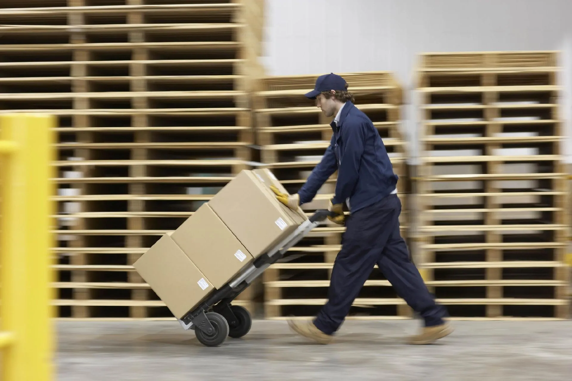 Personale operativo che spinge carrello con scatole per consegne e logistica rapida